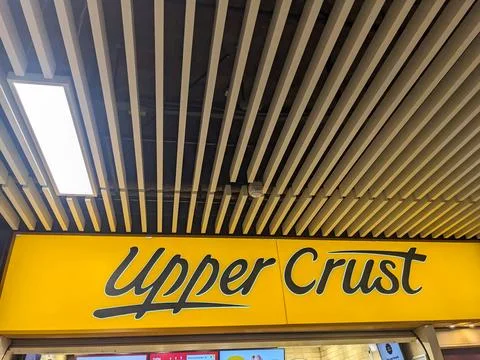 Low angle view of the iconic Upper Crust sign under a modern slatted ceiling in Stock Photos