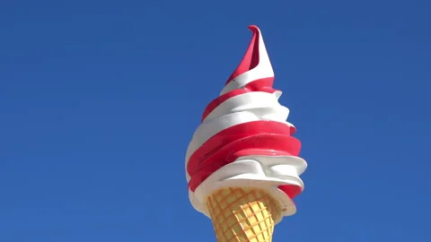 Low angle view of a large decorative red-and-white swirl ice cream cone sign Stock Footage 315247585