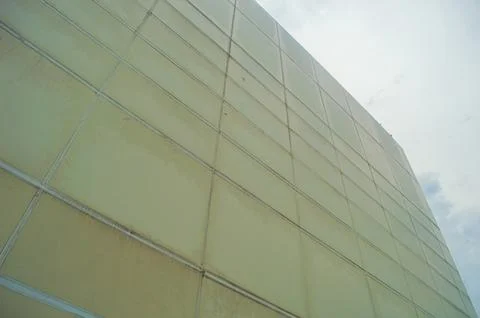 Low angle view of a large, modern building with a pale yellow facade, featu.. Stock Photos