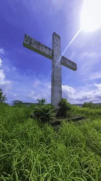 Low-angle view of a large white concrete Catholic cross in an old hillside ce Stock Photos