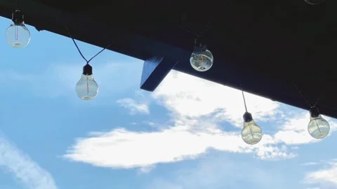 Low-Angle View of Light Bulbs Hanging from Wooden Roof Against Blue Sky Stock Footage 344054888