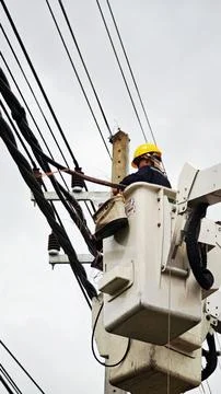 Low angle view of lineman electrician worker in bucket truck basket. Stock Photos