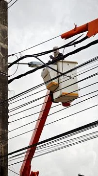 Low angle view of lineman electrician worker in bucket truck basket. Stock Photos