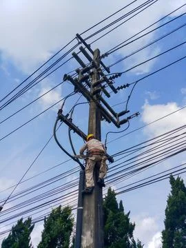 Low angle view of lineman electrician worker with safety harness climbing. Stock Photos