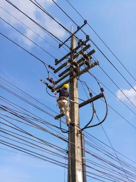 Low angle view of lineman electrician worker with safety harness. Stock Photos