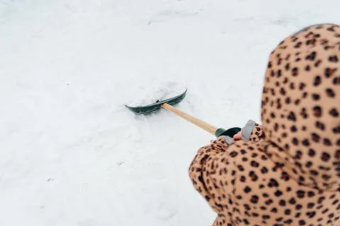 Low angle view of the little kid girl helping to clean pathway from snow with Stock Photos