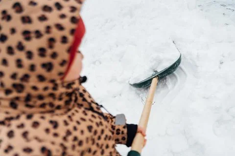 Low angle view of the little kid girl helping to clean pathway from snow with Stock Photos