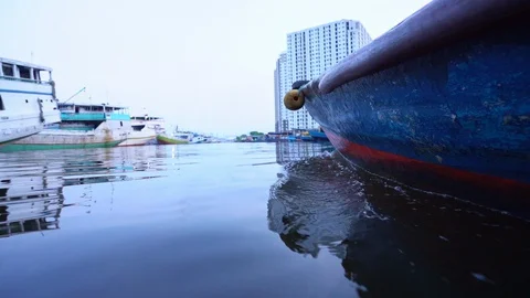 A low angle view of a local fishing boat returning to the Jakarta harbor. 動画素材 128781878