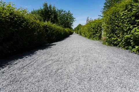 Low angle view of a long straight path with gravel in the sunlight Foto stock