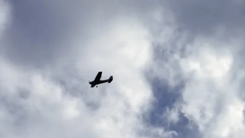 Low angle view, looking up at a single engine plane flying under a cloudy Stock Footage 288942443