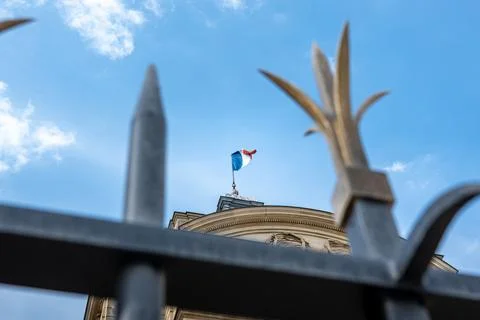 Low angle view looking up through fence at French flag atop cathedral spire Stock Photos