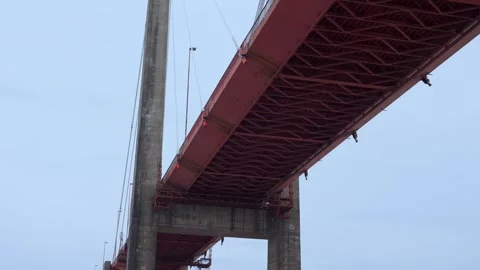 Low angle view looking up at the underside of a large red metal bridge Stock Footage 345936037