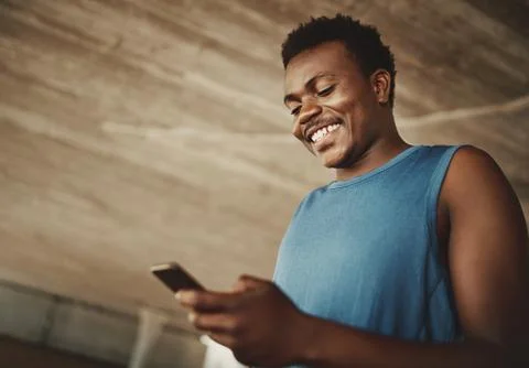 Low angle view of a male runner texting messages on mobile phone at outdoors Stock Photos