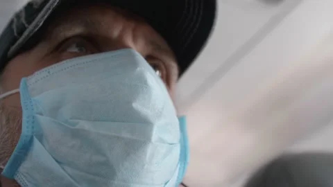Low angle view of man in cap wearing medical mask sitting in plane. Stock Footage 130404165