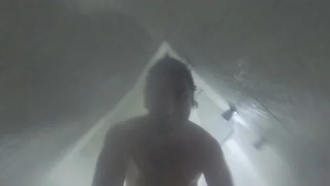 Low angle view of a man cleaning the camera taking a shower in a hotel room seen 库存影片 197091942