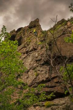 Low angle view of a man climbing on cliff against dramatic sky 스톡 사진