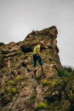 Low angle view of a man descending from the cliff against grey sky 스톡 사진