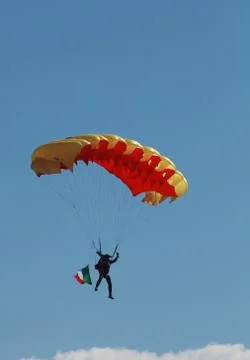 Low angle view of a man floating through a blue sky with a parachute. 스톡 사진