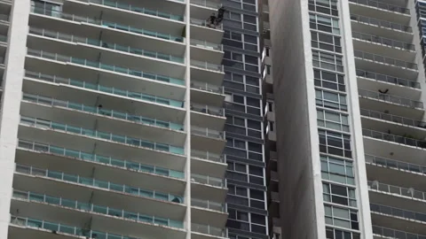 Low-Angle View Of A Man Jumping From A Highrise Building Balcony And Deploying Stockbeeldmateriaal 196900191