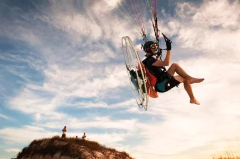 Low angle view of man paragliding against sky Foto stock