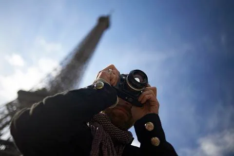 Low angle view of man photographing through DSLR camera against Eiffel Tower and 写真素材