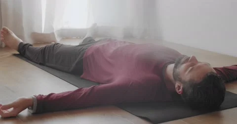 Low angle view of man relaxing in shavasana asana indoors natural morning light Stock Footage 140899469