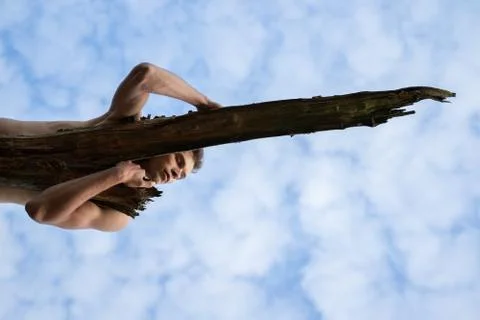 Low angle view of man sleeping on log against cloudy sky in forest Stock Photos