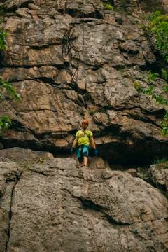 Low angle view of man throwing rope from the cliff against brown cracked rock Stock Photos
