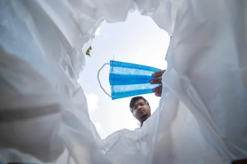 Low angle view of a man throwing disposable surgical mask into the bin.  Stock Photos