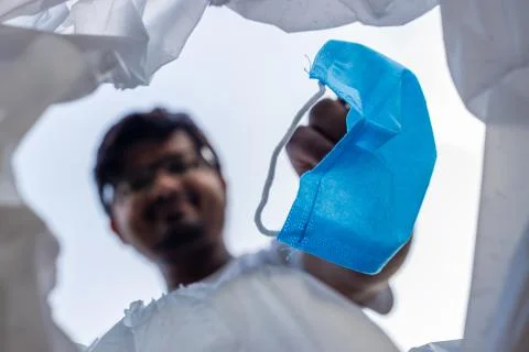 Low angle view of a man throwing disposable surgical mask into the bin.  Stock Photos