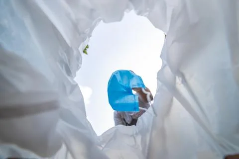 Low angle view of a man throwing disposable surgical mask into the bin.  Stock Photos