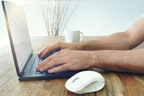 Low angle view of man using laptop computer on wooden table with bright sunlight Stock Photos