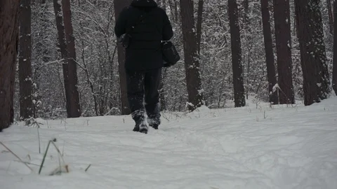 Low angle view on the man walking in the winter forest with his smartphone to Stock Footage 101120138