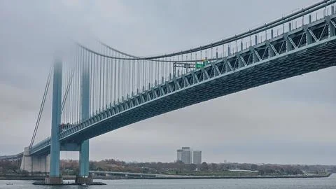 Low angle view of a massive steel suspension bridge disappearing into thick.. Stock Photos