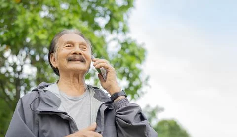 Low angle view of mature man standing outdoors using mobile phone with copy.. Stock Photos