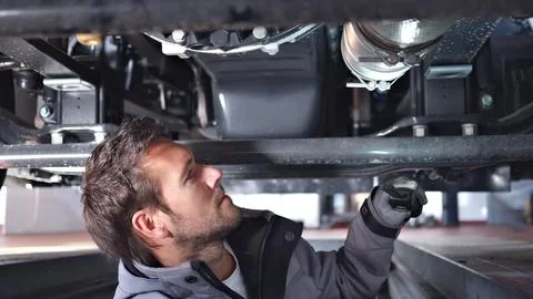 Low Angle View of Mechanic Inspecting Vehicle Undercarriage with Tools Stock Photos