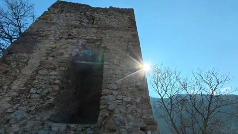 Low-Angle View of Medieval Tower with Sun Peeking Behind – Autumn Forest Stock Footage 330958903