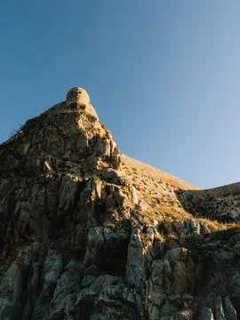 Low angle view of medieval watchtower atop rugged cliff, glowing in warm light Stock Photos
