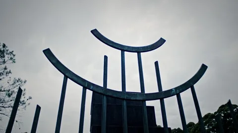 Low-angle view of a modern, abstract metal gate structure at a cemetery Stock Footage 331437213