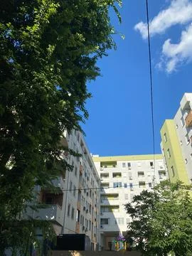 Low-angle view of modern apartment buildings framed by lush green trees Stock Photos