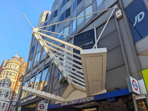Low angle view of the modern Bond Street Station entrance next to historic Stock Photos