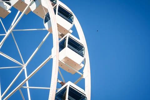 Low angle view of modern Ferris wheel gondolas against deep blue 스톡 사진