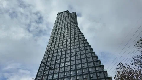 Low-Angle View of Modern Glass Skyscraper Against Dramatic Cloudy Sky. Stock Footage 322170713