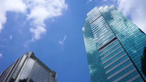 Low Angle View of Modern Glass Skyscrapers and Fast Moving Clouds on Blue Sky Video stock 337943439