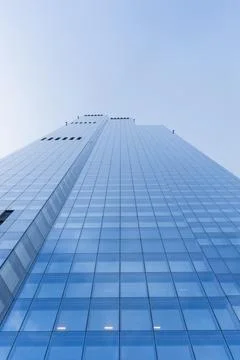 Low angle view of modern glass skyscraper against blue sky 库存照片