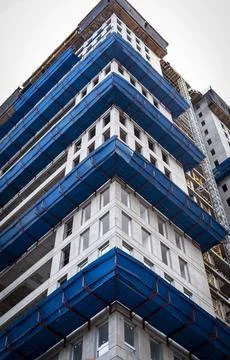 Low angle view of modern high rise building construction site with blue saf.. Stock Photos