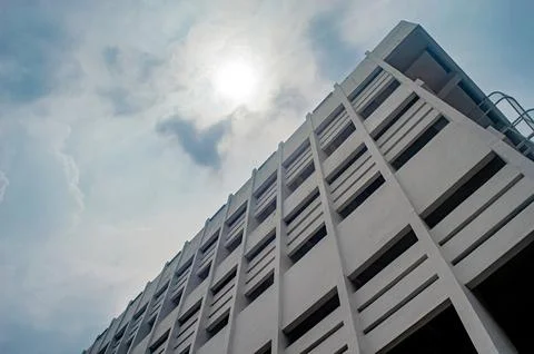 A low angle view of a modern multi story building against a cloudy sky with.. Stock Photos