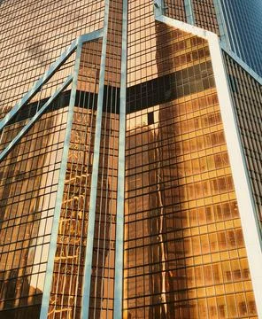 Low angle view of modern skyscraper with reflective golden glass facade Stock Photos