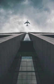 Low angle view of modern tall business building. Commercial jet plane flying Stock Photos