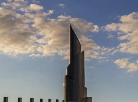 Low angle view of a modern twisting metal tower spire against a cloudy suns.. Stock Photos